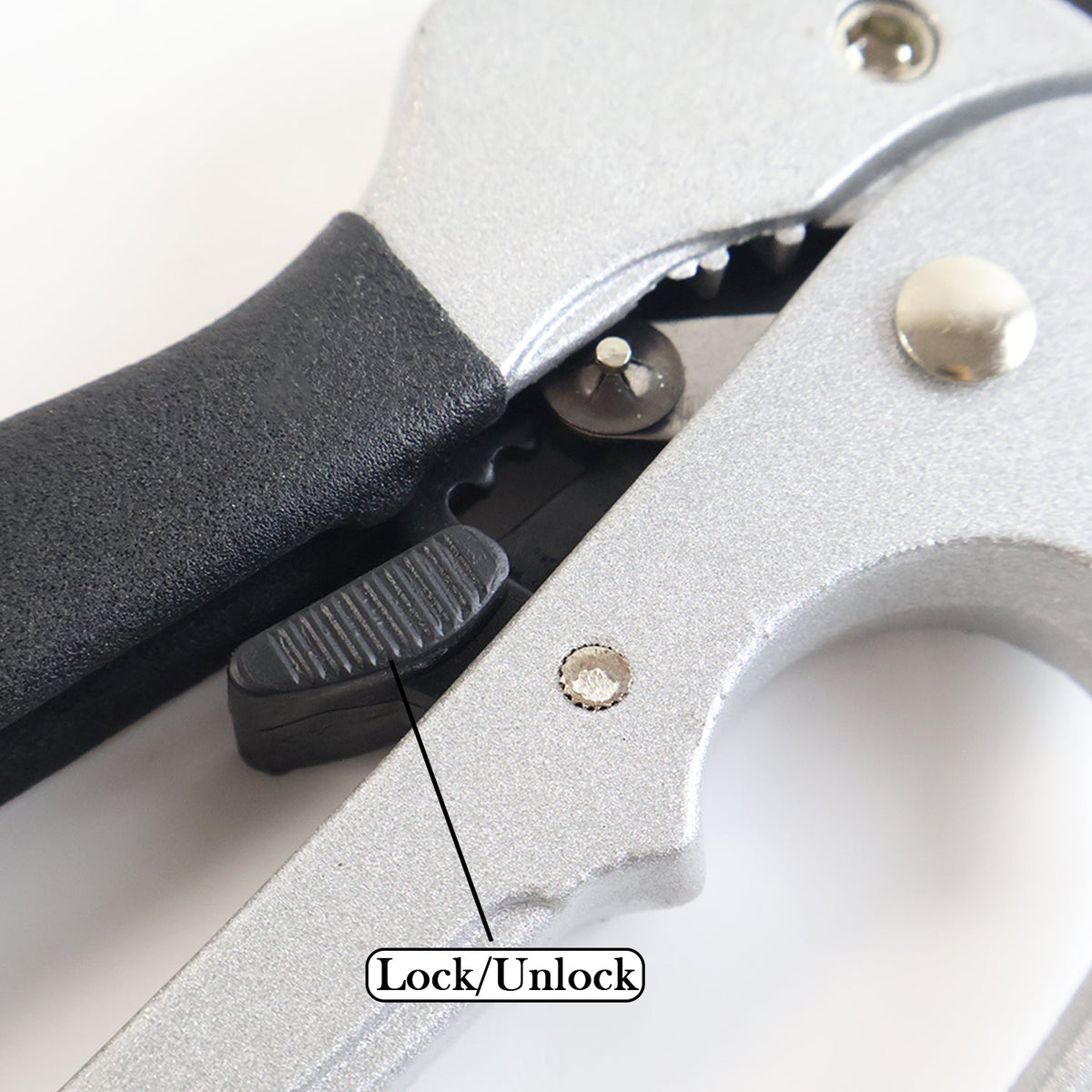 Close-up of the pruning shears' lock/unlock mechanism with a textured black switch.