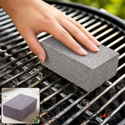 A hand holding a gray cleaning block, scrubbing a dirty metal grill grate with hot coals visible below.