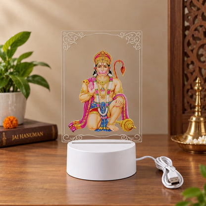 A Hanuman LED acrylic night lamp on a wooden surface, showing the USB cable and a decorative brass item.
