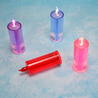 Three upright LED crystal candles in purple, blue, and pink, with one red candle lying down on a light blue surface.