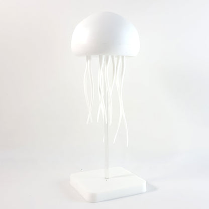 A white jellyfish lamp with a clear stand and square base, presented against a plain white background.