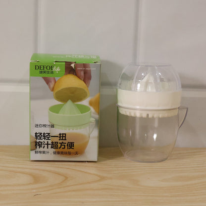 A boxed citrus juicer next to the actual white and clear plastic manual citrus squeezer on a wooden surface.