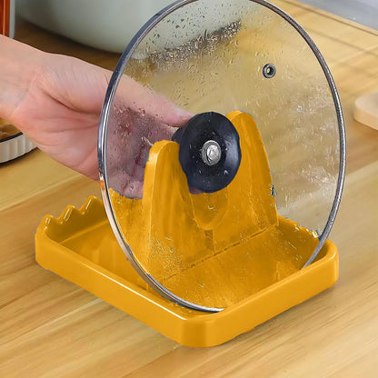 A hand adjusting a glass pot lid with a black handle on a yellow plastic lid and spoon rest on a wooden surface.