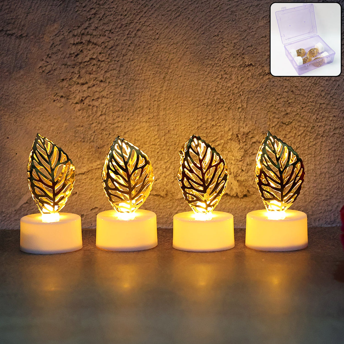 Four golden leaf LED candles glow warmly on a surface against a rustic wall.