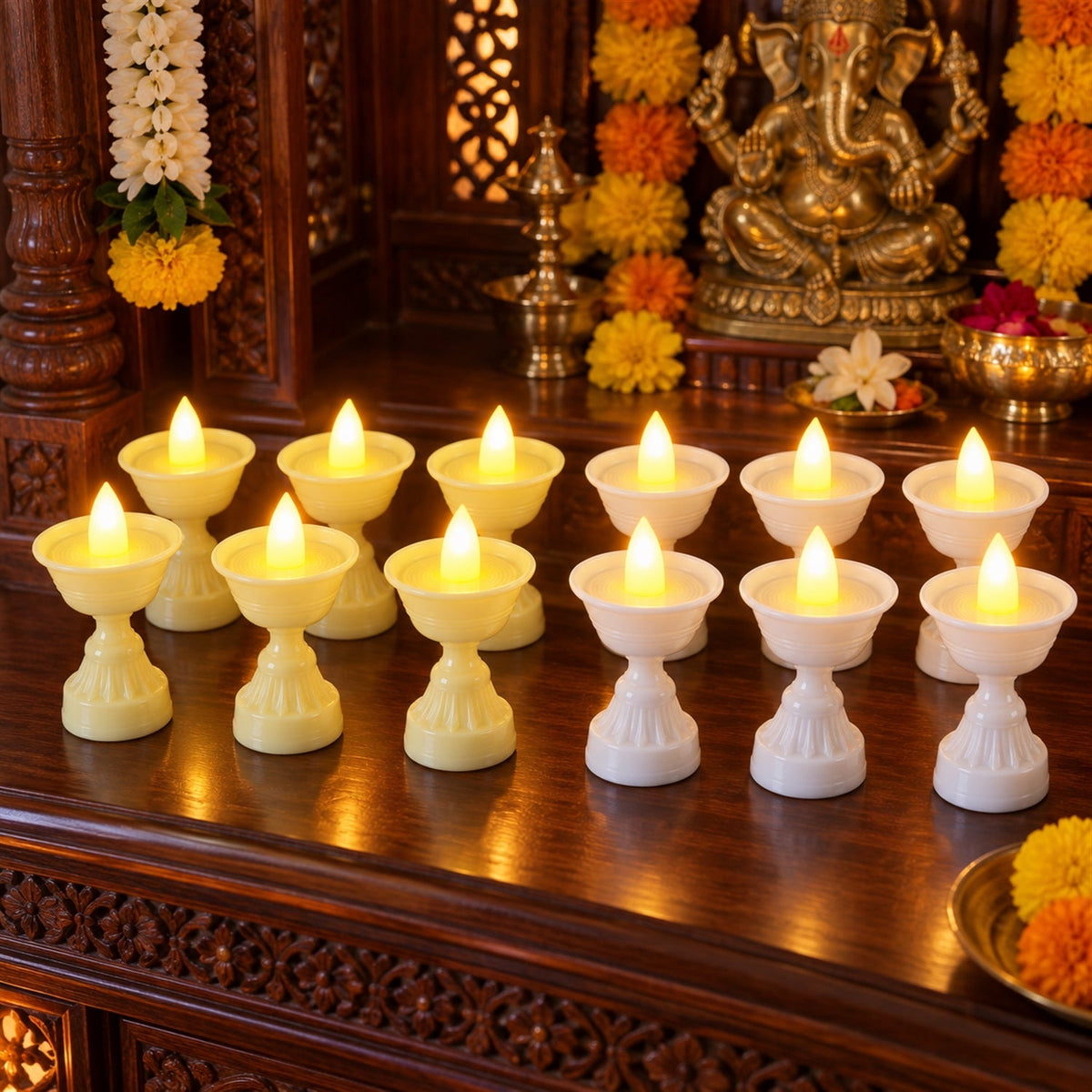 A dozen LED diya candles, in yellow and white, glow on a dark wooden surface before a decorated Hindu shrine.