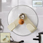 A cream-colored, adjustable pot lid holder with a wooden knob and chrome accent holds a clear glass lid on a white tiled