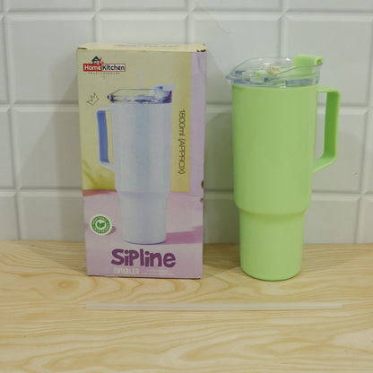 A light green travel tumbler with a handle, lid, and straw is displayed next to its product box on a wooden surface.