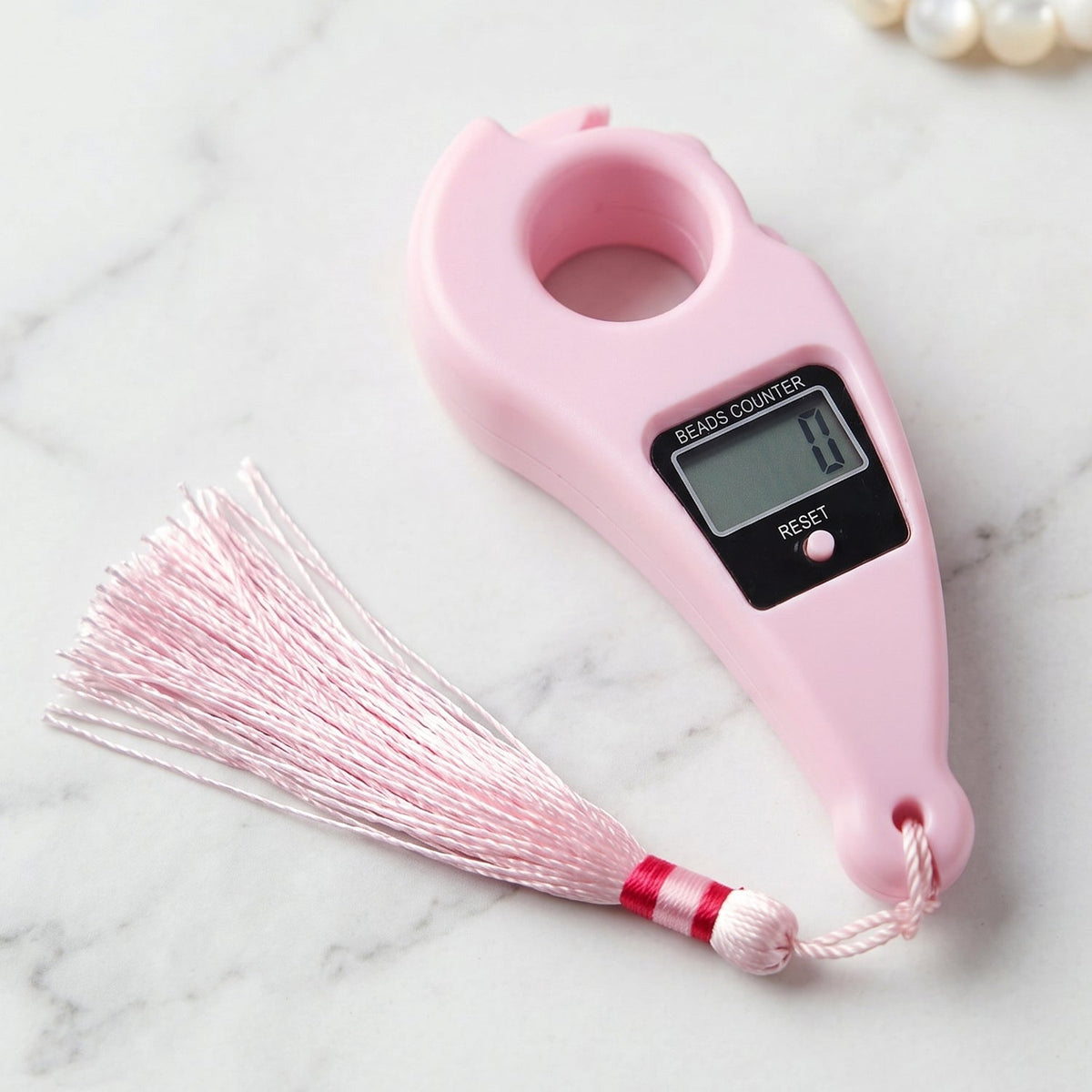 Pink digital finger ring beads counter with a matching pink tassel, shown on a white marble surface.