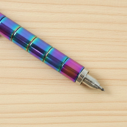 A close-up of the tip of a rainbow-colored magnetic fidget pen on a light wooden surface.