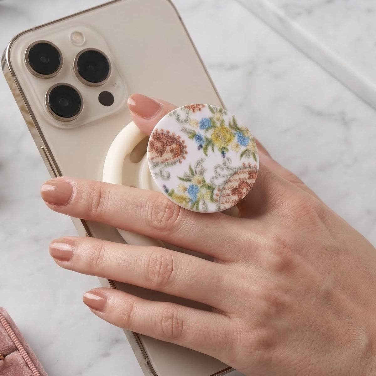 A hand holds a white smartphone with a round pop socket featuring a white background and colorful paisley floral – view 10