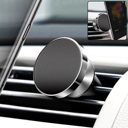 A close-up of a black and silver magnetic car mount on an air vent, with a phone visible in the background.