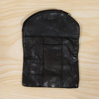 A black leather pouch with a top zipper and vertical seam details, laid flat on a light wooden surface.