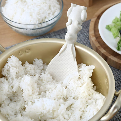 A white bunny-handled rice spoon is placed in a gold pot filled with white rice, ready for serving.