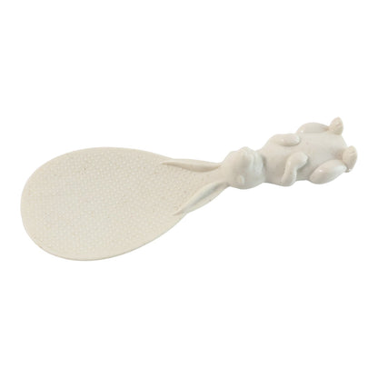 A white bunny-handled rice spoon is shown lying flat against a white background, highlighting its textured surface.