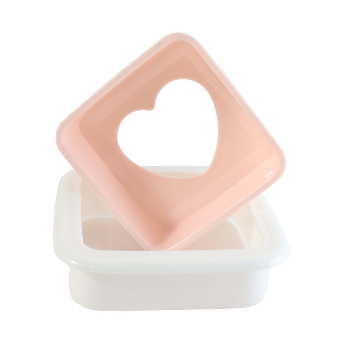 Pink heart-shaped top of a sandwich cutter resting on its white base, isolated on a white background.