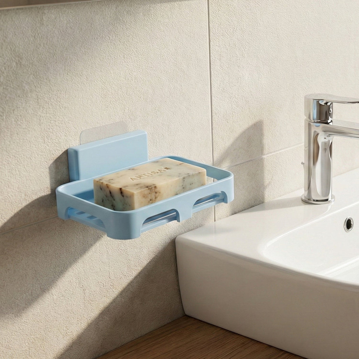 Light blue plastic soap dish with a speckled bar of soap, mounted on a tiled wall next to a white sink and faucet.