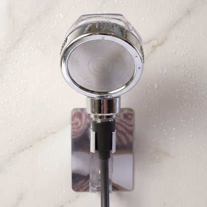 The chrome shower spray head is mounted on a wall bracket, with water droplets visible on the white marble surface.