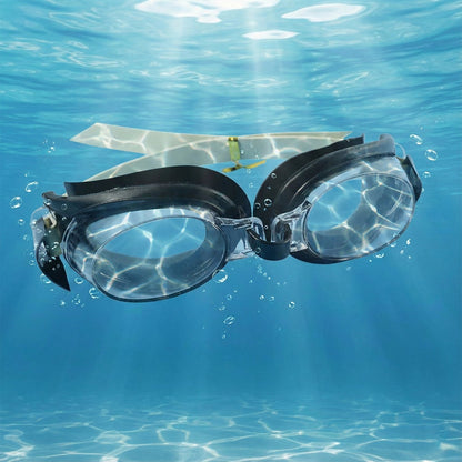 Black and clear swimming goggles with a beige strap submerged underwater with light rays and bubbles.