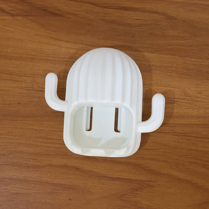White cactus toothbrush holder with two slots, resting on a light brown wooden surface.