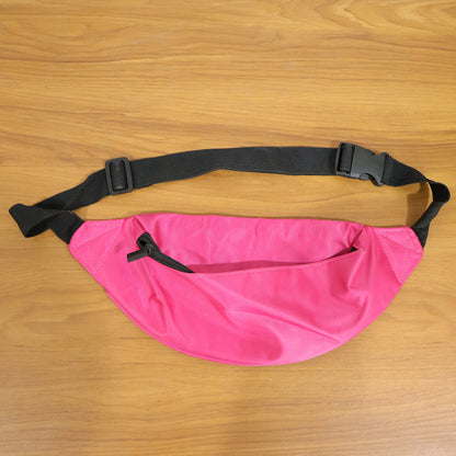 A bright pink fanny pack with an open front zipper and black strap rests on a wooden table.