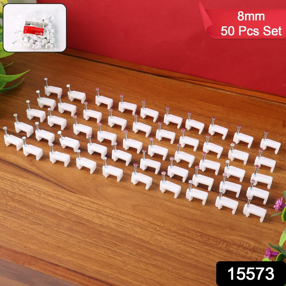 Fifty white plastic cable clips with nails arranged in neat rows on a wooden surface, with a small bag of clips in the top