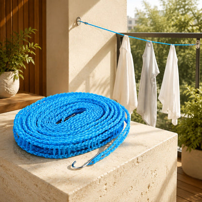 A coiled blue clothesline with a metal hook rests on a stone surface, with clothes drying on a line in the background.