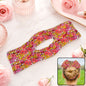 Pink and yellow floral hair bun maker on a marble surface with pink roses and perfume bottles.