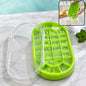 A green oval silicone ice cube tray with a clear lid, filled with ice, next to a glass of ice water.