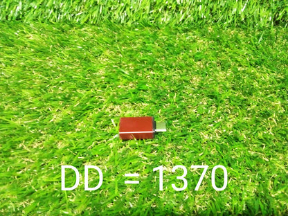 A small red USB-C to USB 3.0 OTG adapter is centered on a vibrant green artificial grass background.