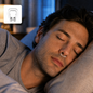 A man sleeps soundly with a clear anti-snoring nose clip inserted, a small inset shows the clip alone.
