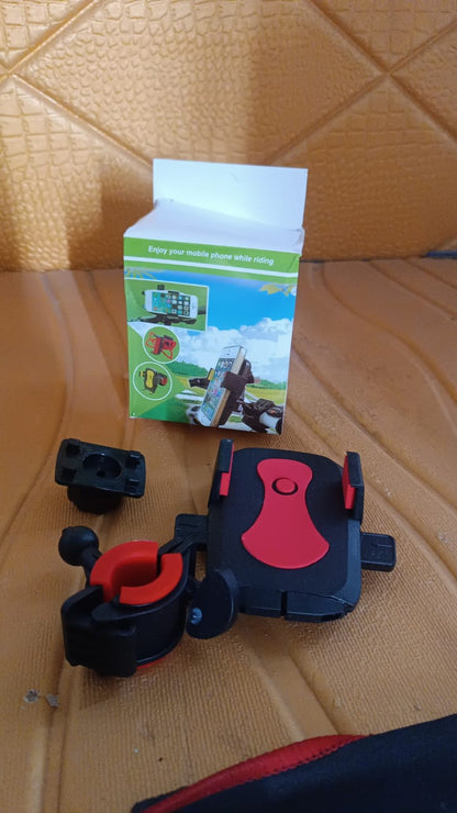 Black and red phone mount components and its green and white packaging box on a brown textured surface.