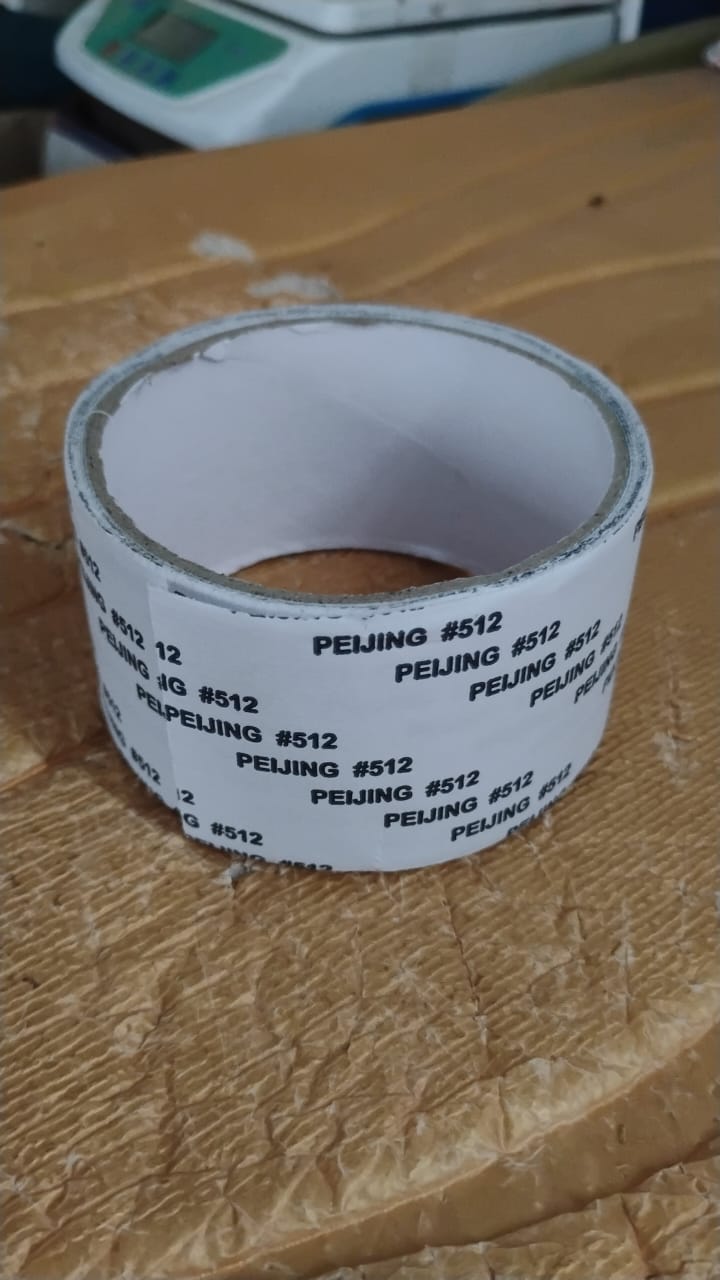 A roll of grey mesh repair tape with white backing, sitting on a textured brown surface.