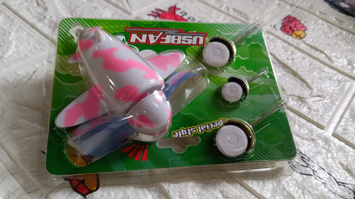 The pink and white airplane USB fan and its three wheels are sealed in clear plastic packaging with a green backing.