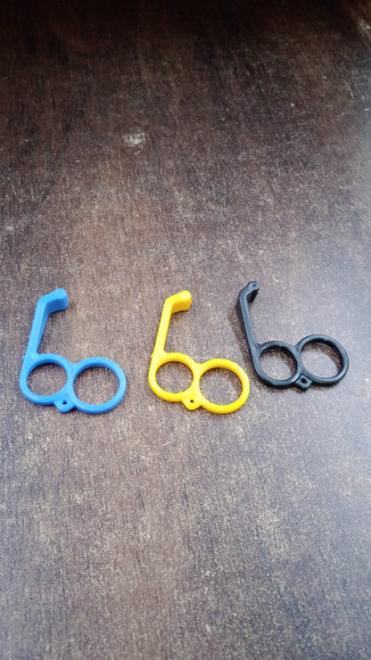 Three plastic finger ring phone holders in blue, yellow, and black are arranged on a dark wooden surface.