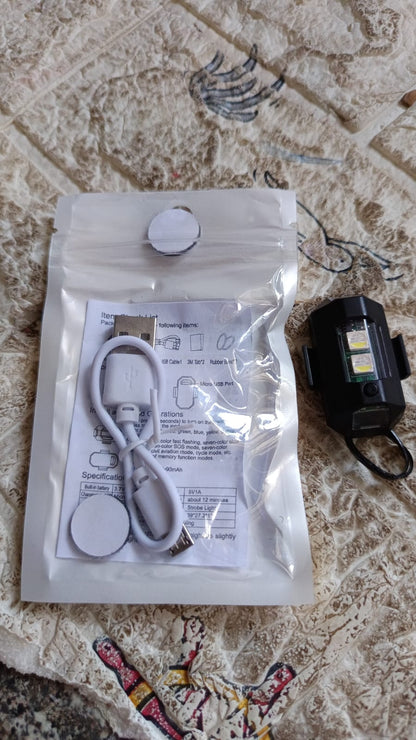 One black LED strobe light and a clear plastic bag containing a USB cable and instructions on a patterned surface.