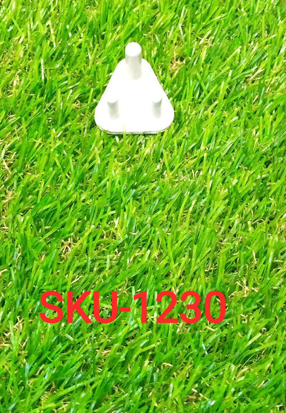 A single white child-proof plug with three prongs resting on bright green artificial grass.