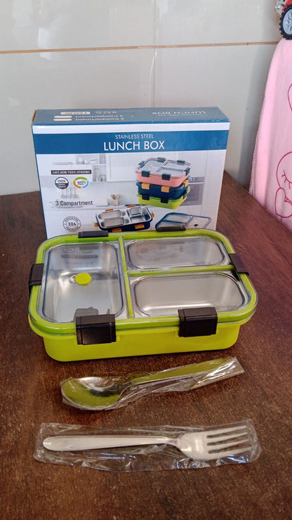A green three-compartment stainless steel lunch box with dark clips, a spoon, fork, and its packaging box.