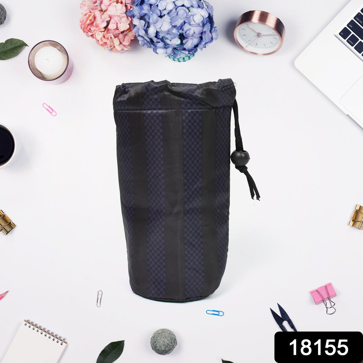 A navy blue drawstring pouch with vertical stripes stands upright on a white surface surrounded by office supplies and