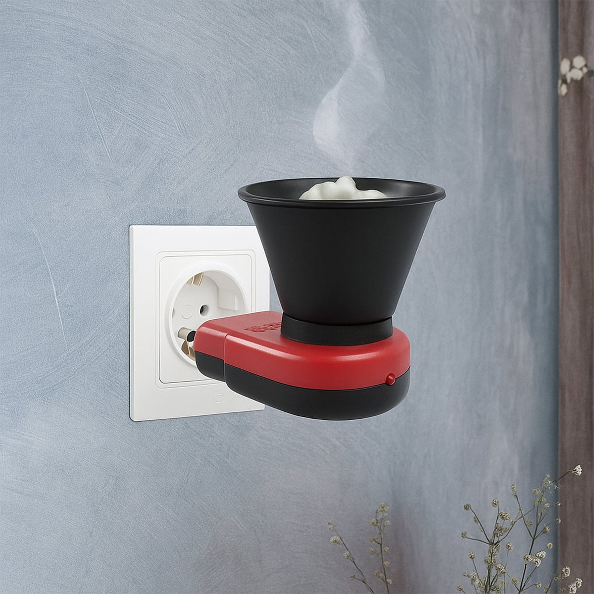A red and black electric Kapoor Dani diffuser plugged into a white wall socket, with white camphor pieces inside.