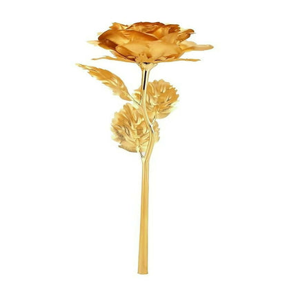 A detailed view of a gold-plated rose with a long stem and multiple leaves on a white background.