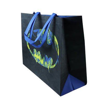 Angled view of a black reusable tote bag with a distressed neon green and blue Batman logo and blue sides.