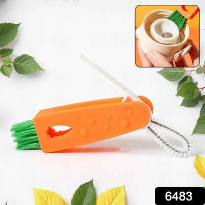 The orange 3-in-1 cleaning brush with green bristles and a white crevice tool rests on a white surface with green leaves.