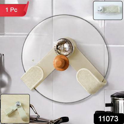 The cream-colored pot lid holder with a wooden knob and chrome accent is mounted on a white tiled kitchen wall.