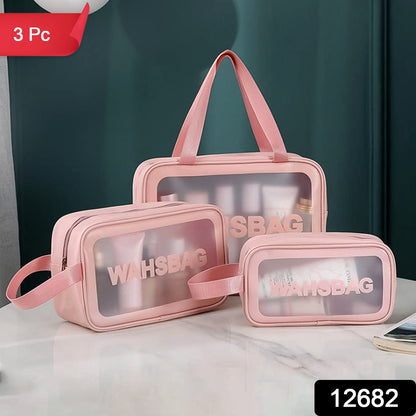 Three pink waterproof travel bags with clear panels on a white table, with a dark green wall in the background.