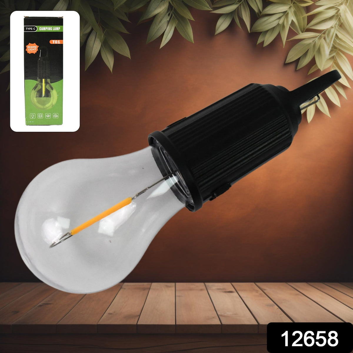 A clear LED bulb with a black top and hook lies on a wooden surface, with its green and black packaging in the top left.