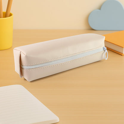 Closed beige pencil case on a light wooden desk with a yellow pen holder and blue cloud decor.